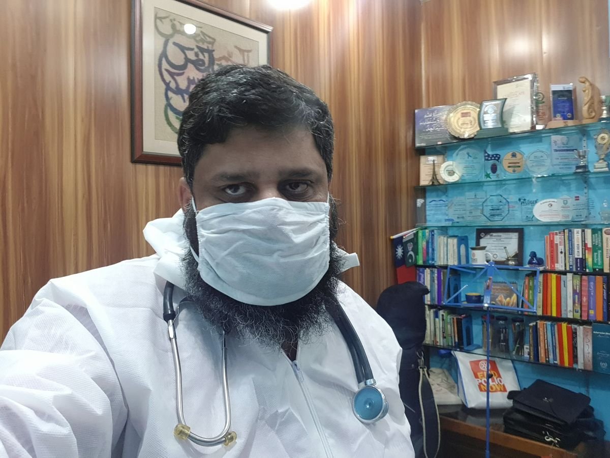 Dr. Ahmed Ejaz in protective gown and mask in his office