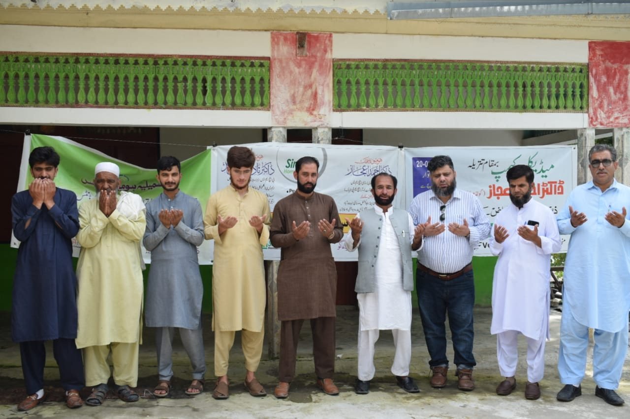 Volunteers and organizers raising their hands in prayer before the camp
